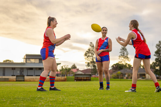three female footballers practising ball handling skills at sunset