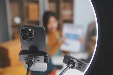 vlogger, blogger small SME business asian beautiful woman using mobile phone video call for sell clothes live stream selling online, show product present detail at home office, entrepreneur ecommerce