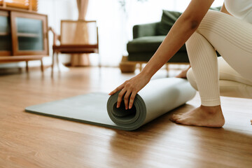 Young Asian woman doing yoga, twisting on a mat in the living room at home