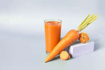 Carrot juice and carrots in close-up and decorative elements in close-up on a light background