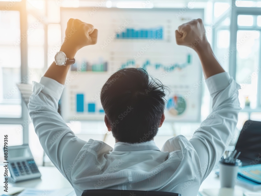 Poster rear view of a businessperson celebrating success in front of a screen with financial charts in a mo
