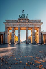 Brandenburg Gate captured on a sunny autumn day with fallen leaves. Berlin's historic gate under clear skies.