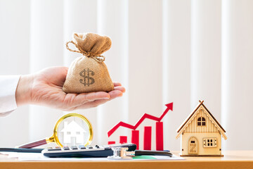 Businessman hand hold the money bag and magnifying glass searching a home and red arrow and bar...