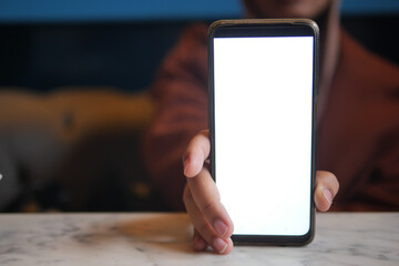 Person holds smartphone with blank screen on table, symbolizing modern technology