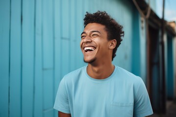 Fototapeta premium Close-up portrait of a cheerful man wearing an blue shirt and glasses, laughing joyfully against a dark background. 