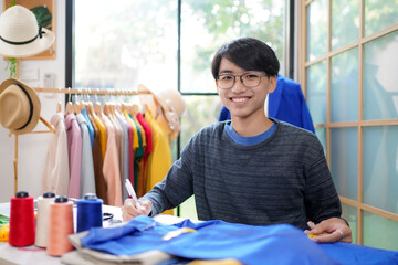 Trainee asian teenage man fashion designer  vocation and  education work on designer in the showroom,  Lifestyle Stylish tailor clothing design and cutting cloths in studio.  Education Concept