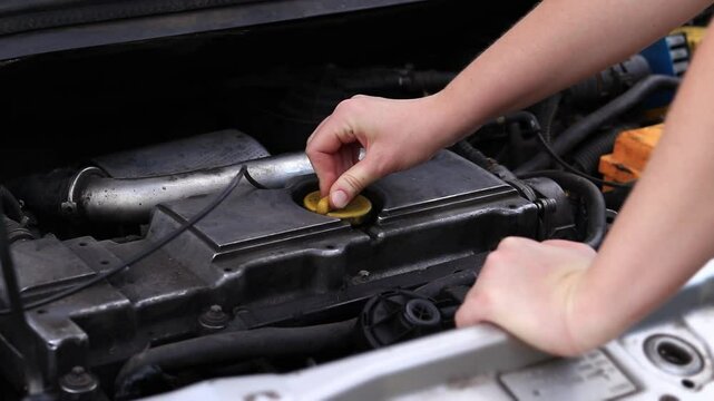 Change of oil. A woman's hand opens or closes the oil filler cap. Changing the oil in a diesel car engine. Car maintenance. Old car