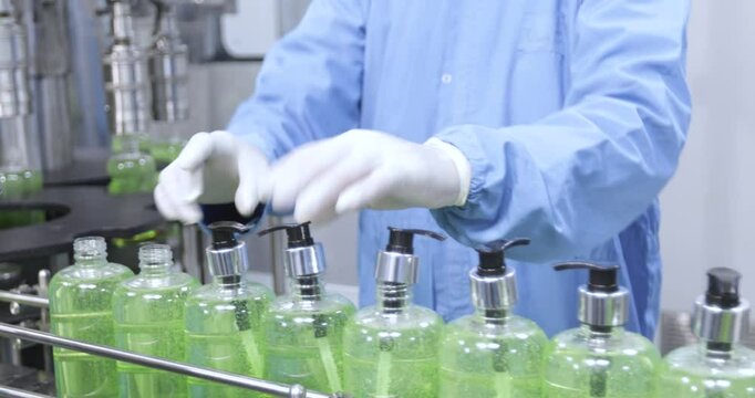 bottle nozzle cap fixing. chemical liquid sanitiser gel fills in bottles aqueous soap hand wash production line filling making process in a plastic transparent bottle manufacturing factory concept