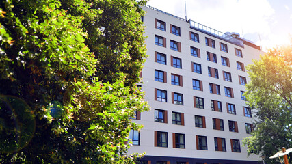 A contemporary multi-story residential apartment building surrounded by lush greenery.