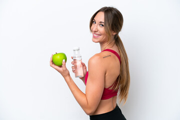 Naklejka premium Young caucasian woman isolated on white background with an apple and with a bottle of water