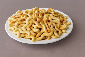 Crunchy organic mini crackers on a plate on a dark pink background