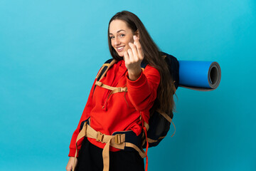 Mountaineer woman with a big backpack over isolated background making money gesture