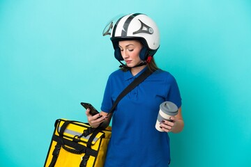 Young caucasian woman with thermal backpack isolated on white background holding coffee to take away and a mobile