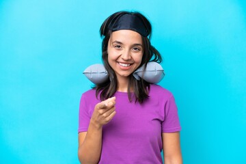 Young caucasian woman with Inflatable Travel Pillow isolated on blue background points finger at you with a confident expression