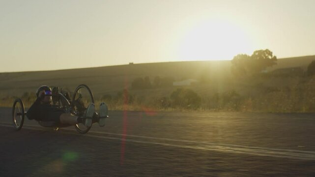 Para Athlete cycling on the road and exercising alone during sunset