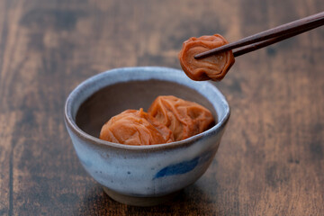 小皿に入った梅干しと箸でつまんだ梅干し