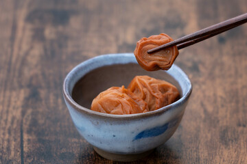 小皿に入った梅干しと箸でつまんだ梅干し