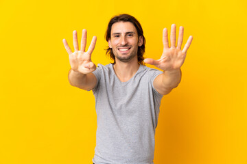 Young handsome man isolated on yellow background counting nine with fingers