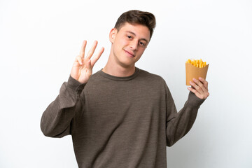 Young Brazilian man holding fried chips isolated on white background happy and counting three with...