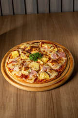 pizza hawaiian on a wooden board