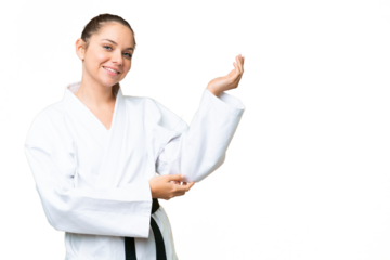 Young blonde woman doing karate over isolated chroma key background extending hands to the side for inviting to come
