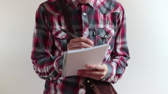 person takes notes, he writing on a block of paper sheets extracted from a vintage shoulder bag
