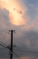 Electric pole on the background of a cloudy sky at sunset.