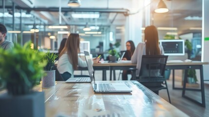 A laptop on a table in a modern office, with blurred people in the background.