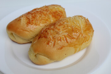 Two baked bread with grated cheese on top, on white plate, isolated on white background