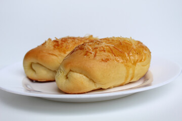 Two baked bread with grated cheese on top, on white plate, isolated on white background