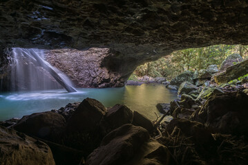 Inside the cave at Natural Bridge in Springbrook National Park, Australia. Waterfall falls through the roof of a cave.
