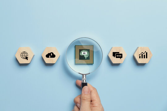 Artificial intelligence AI and machine learning concept.Hand-holding magnifying glass with AI chip inside and business icons on a wooden cube.modern innovation, Futuristic technology transformation.