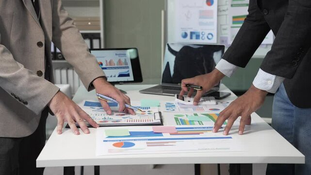 Collaborative meeting at the office desk on teamwork, discussions revolving around financial charts and the management of accounts in the production cost accounting system.