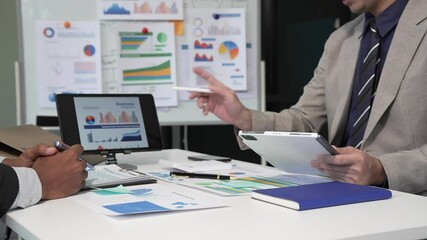 A collaborative meeting at an office desk focusing on teamwork, with discussions centered around financial charts and the sub-account management of work in process in production cost accounting.