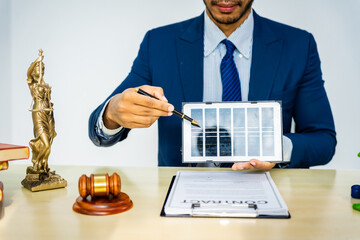 A male Asian lawyer in a formal suit works at his desk, focusing on contracts and legal matters,...