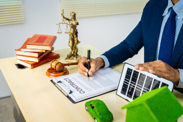 A male Asian lawyer in a formal suit works at his desk, focusing on contracts and legal matters,...