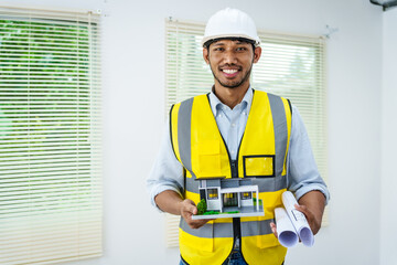 Asian male architect works at desk with house model toy and A3 paper blueprints, construction real estate law, zoning, permits, and resolving property disputes through arbitration and litigation.