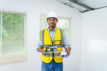 Asian male architect works at desk with house model toy and A3 paper blueprints, construction real estate law, zoning, permits, and resolving property disputes through arbitration and litigation.