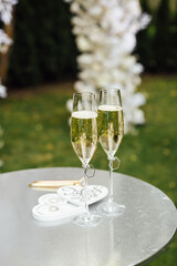 Elegant glasses of champagne for the newlyweds stand on the table next to the ceremony arch