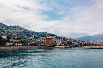Obraz premium Landscape view old walls of fortress and Red tower on Mediterranean coast. View of Alanya Castle, stone ruins in harbor Alanya, Turkey. High quality photo