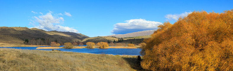 Panoramic view of a lake with autumn trees in the Flat Top Hill Conservation Area, Central Otago, New Zealand
