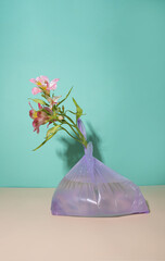 various garbage and among it a pink flower. take care of the planet