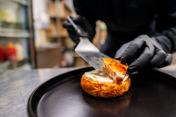 Close-up of hands spreading cream on a halved bagel with a metal spatula