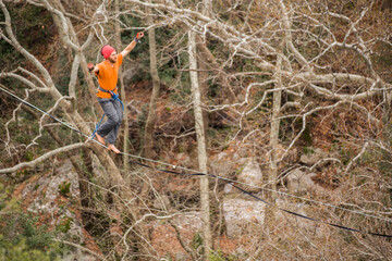 A man walks on a tightrope over an abyss.