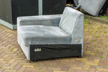 black and gray sofa is left outside as rubbish on the street