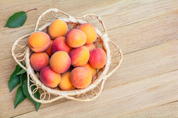 Fresh ripe apricots in a wicker bowl on a wooden table