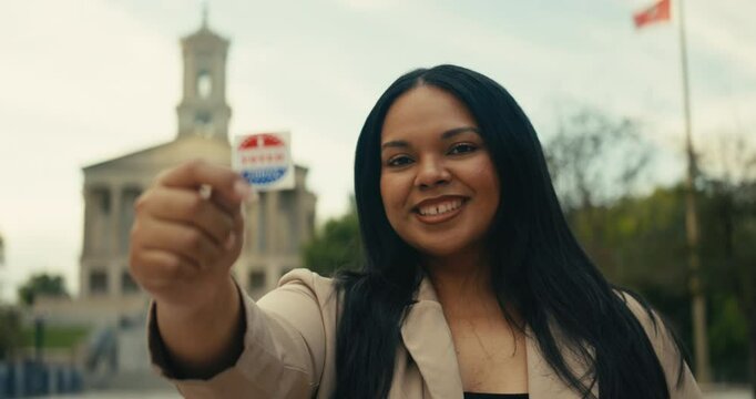 Young woman smiling with an &lsquo;I Voted&rsquo; stickers and pin 