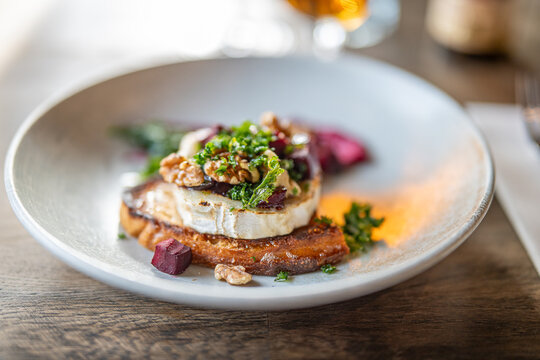Ch&egrave;vre chaud toast with beetroots, roasted walnuts and dried kale on sourdough bread served as a starter