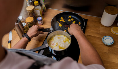 Chef at the kitchen preparing pumpkin porridge with tofu and vegetables