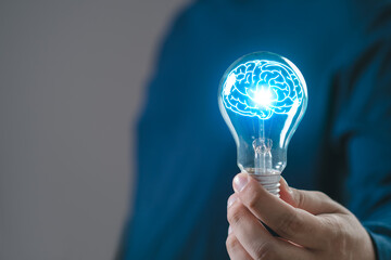 Person holding a light bulb with a glowing brain inside. Concept of creativity, innovation, and...